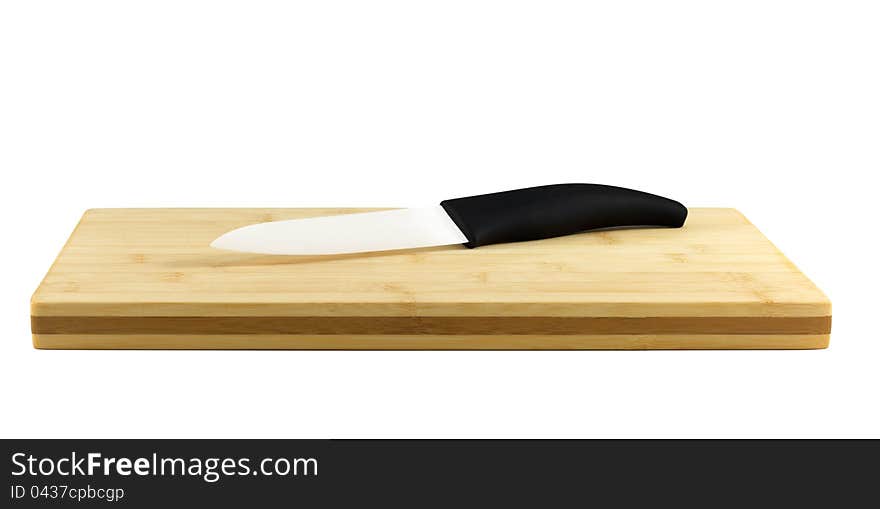 Ceramic Knife on a chopping board isolated on white. Ceramic knives will not corrode in harsh environments, are non-magnetic, and do not conduct electricity. Their resistance to strong acid and caustic substances, and their ability to retain a cutting edge longer than forged metal knives, make them a suitable culinary tool for slicing boneless meat, vegetables and fruit.