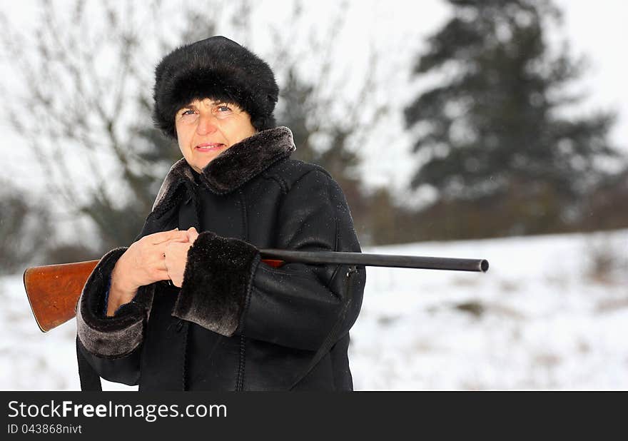 A female hunter with a shotgun in a forest during winter season. A female hunter with a shotgun in a forest during winter season