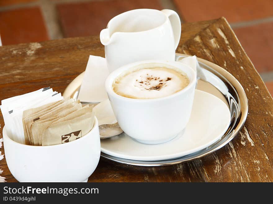 Cup of steaming cappucino coffee with frothed milk and sugar and chocolate shavings. Cup of steaming cappucino coffee with frothed milk and sugar and chocolate shavings