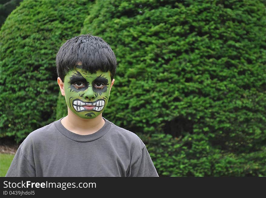 A young kid with a painted face is looking to the camera, mad or sad. A young kid with a painted face is looking to the camera, mad or sad.