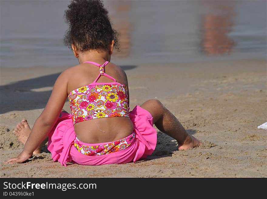 A little girl is on a beach shore finding and collecting shells, stones, and another treasures. A little girl is on a beach shore finding and collecting shells, stones, and another treasures.