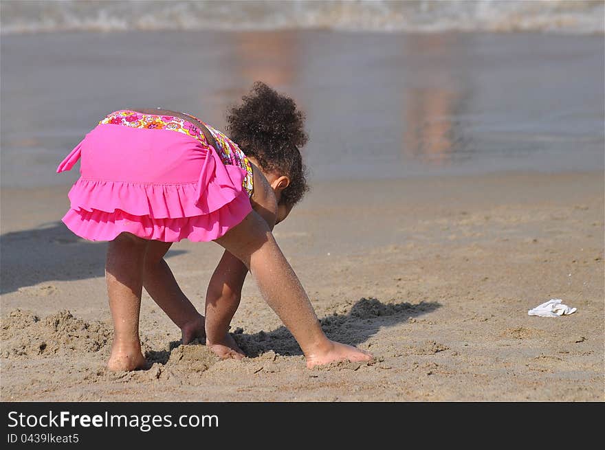 A curious little girl is at a beach shore looking for shells. A curious little girl is at a beach shore looking for shells.