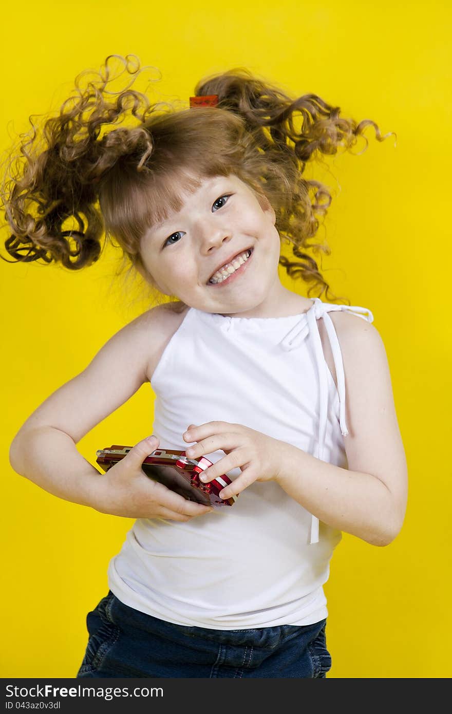 Little girl playing handheld portable game console. Yellow background. Little girl playing handheld portable game console. Yellow background