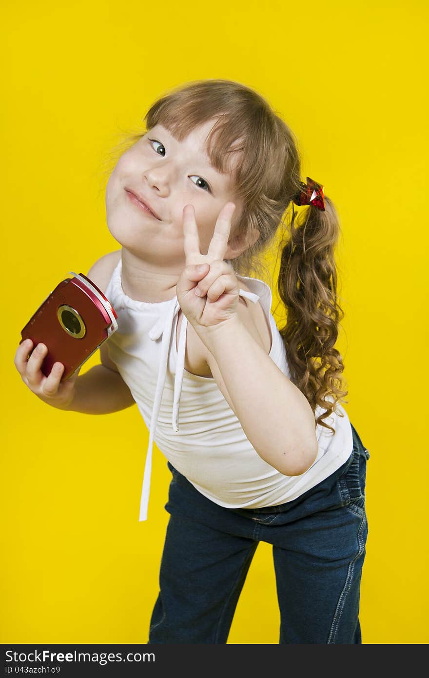 Little girl playing handheld portable game console. Yellow background