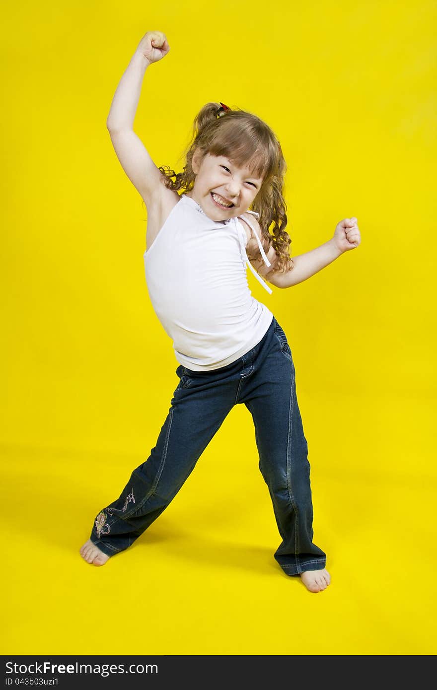 Cheerful girl dances on a yellow background. Cheerful girl dances on a yellow background