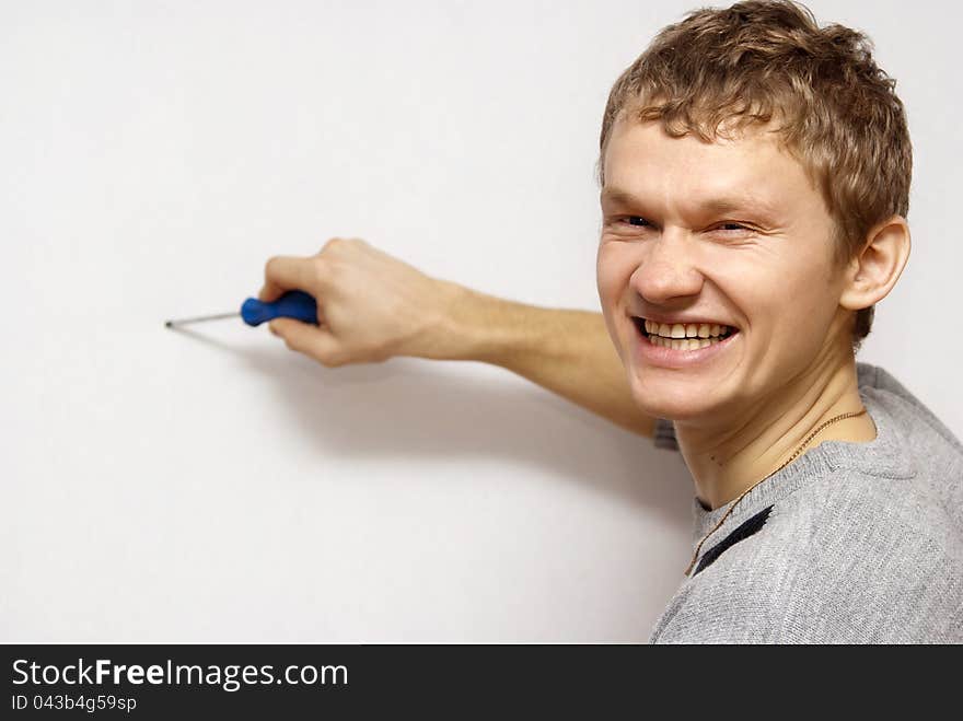 The gray background of the boy holds in his hands a screwdriver. The gray background of the boy holds in his hands a screwdriver