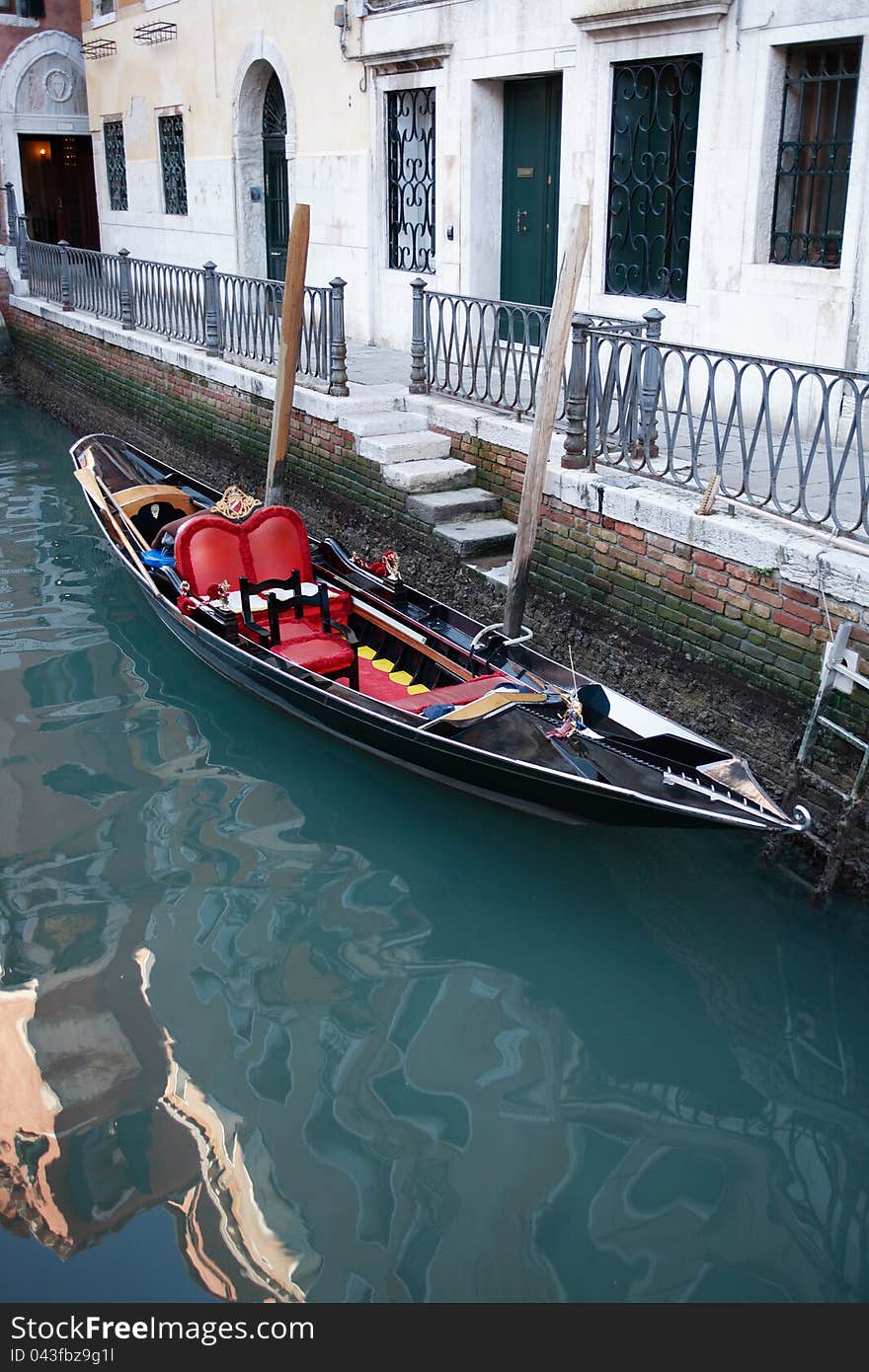 Empty gondola tied to building wall on a canal in Venice, Italy. Empty gondola tied to building wall on a canal in Venice, Italy