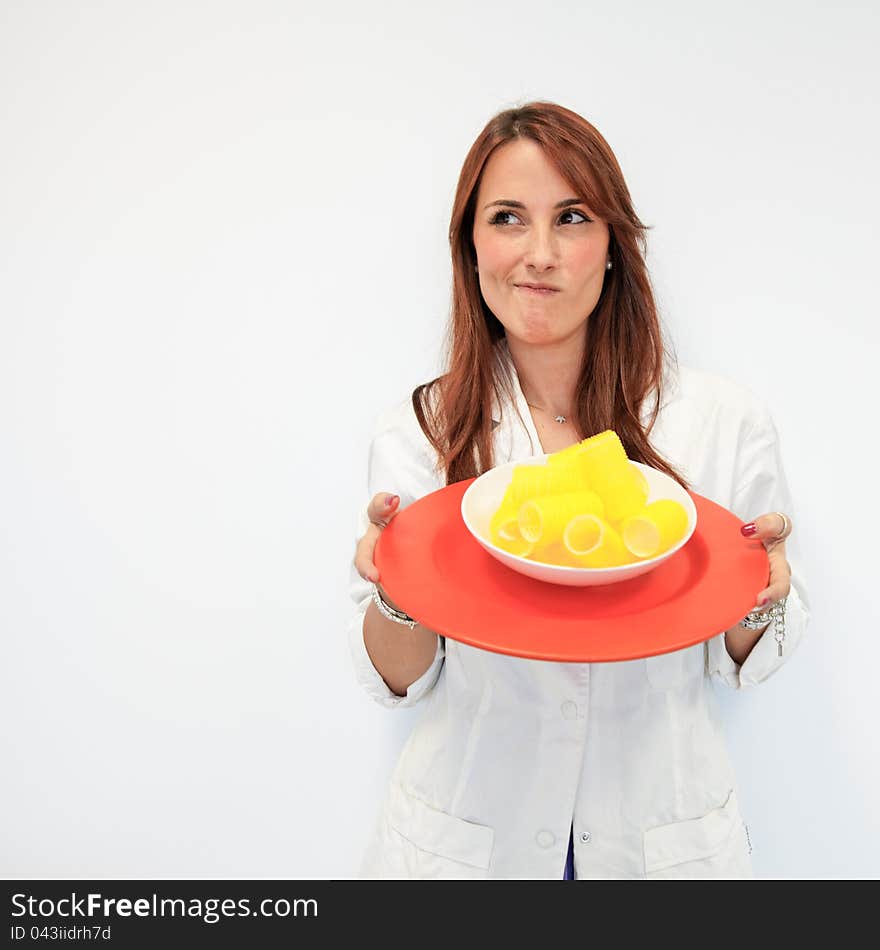 Beautiful woman doctor offering a dish of curlers instead of food for a fashion diet. Beautiful woman doctor offering a dish of curlers instead of food for a fashion diet