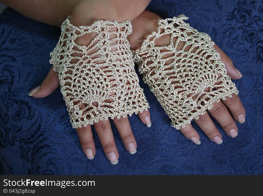 Hands of Alaska Native woman wearing fancy fingerless gloves made with crochet pineapple stitch design.