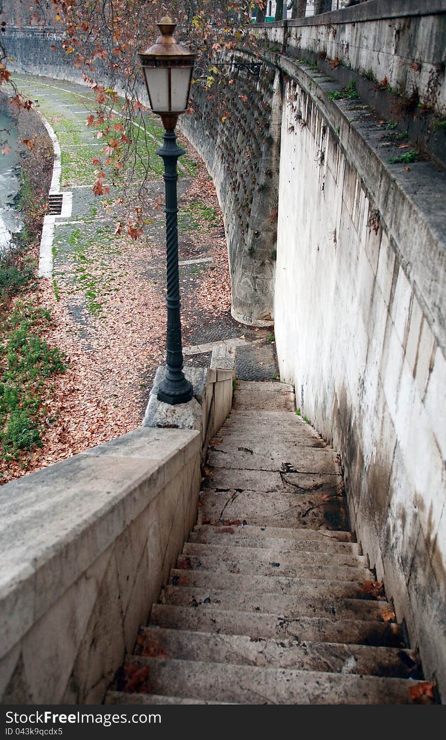 Urban scene with old stone staircase and street lamp near river