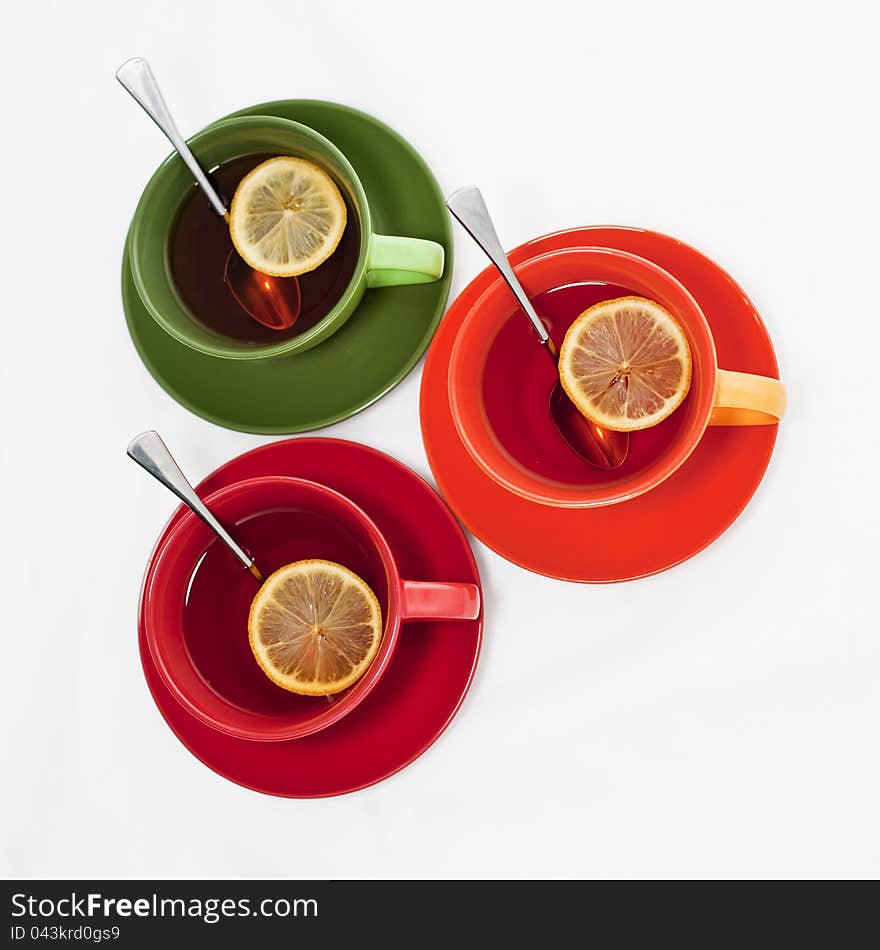 Three colored tea cups with tea and lemon