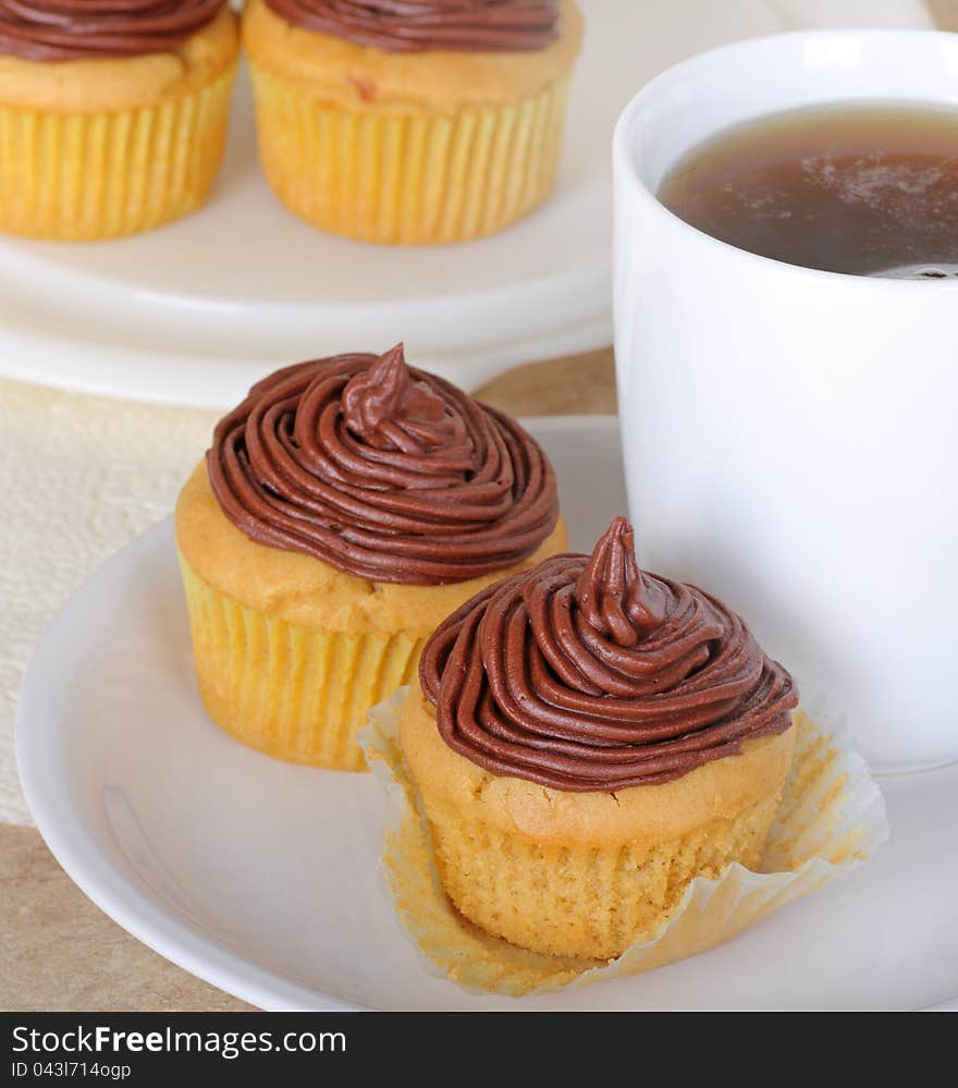 Chocolate frosted cup cakes with a cup of coffee