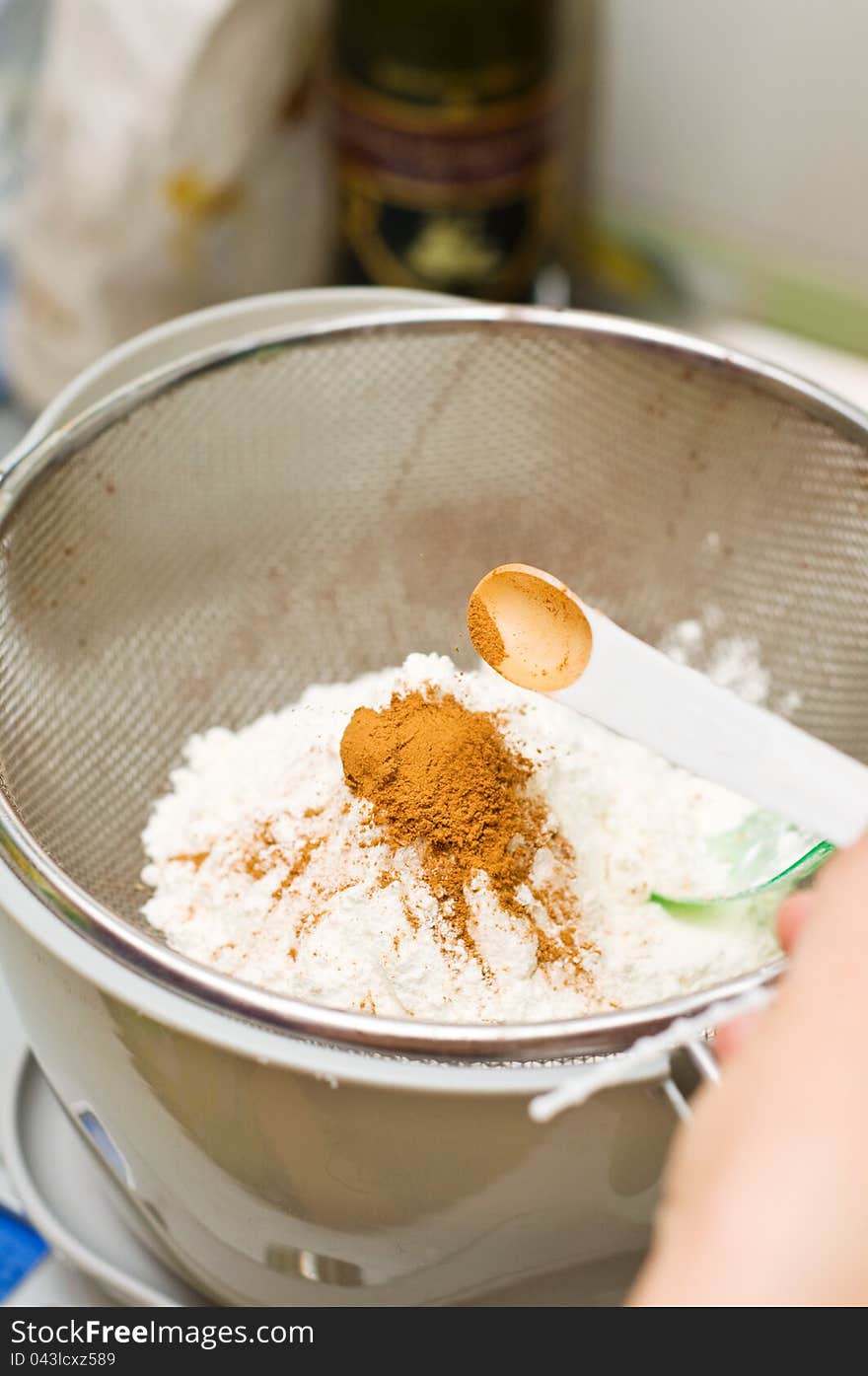 Mixing cocoa powder with sugar for cooking on a strainer.