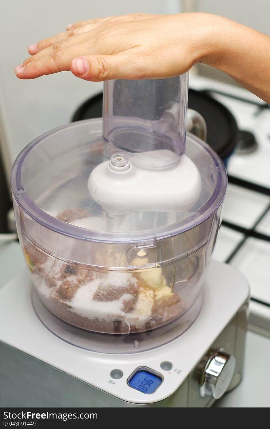 A chef mixing ingredients for a cake in a blender with hand on top. A chef mixing ingredients for a cake in a blender with hand on top.