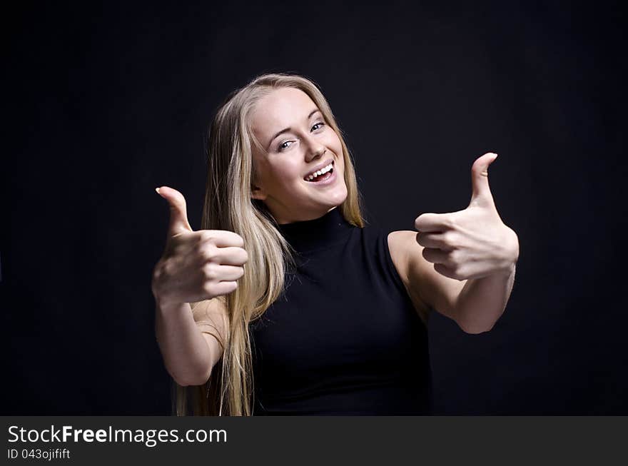 YOUNG FEMALE SHOWING A THUMBS UP ON BLACK. YOUNG FEMALE SHOWING A THUMBS UP ON BLACK