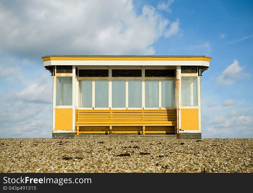 Weathered beach storm shelter against a blue cloudy sky