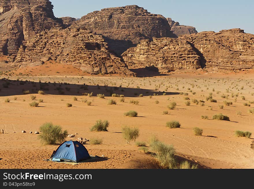 Lone tent in the Wadi Rum UNESCO World Heritage desert area. Long shadow from a towering peak.