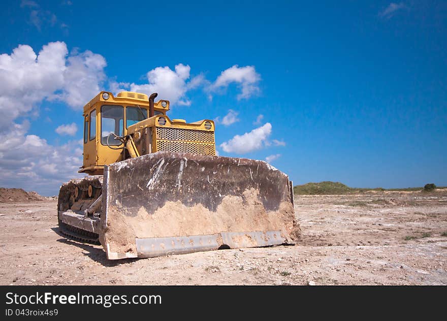 Orange bulldozer after the work is on a background of blue sky