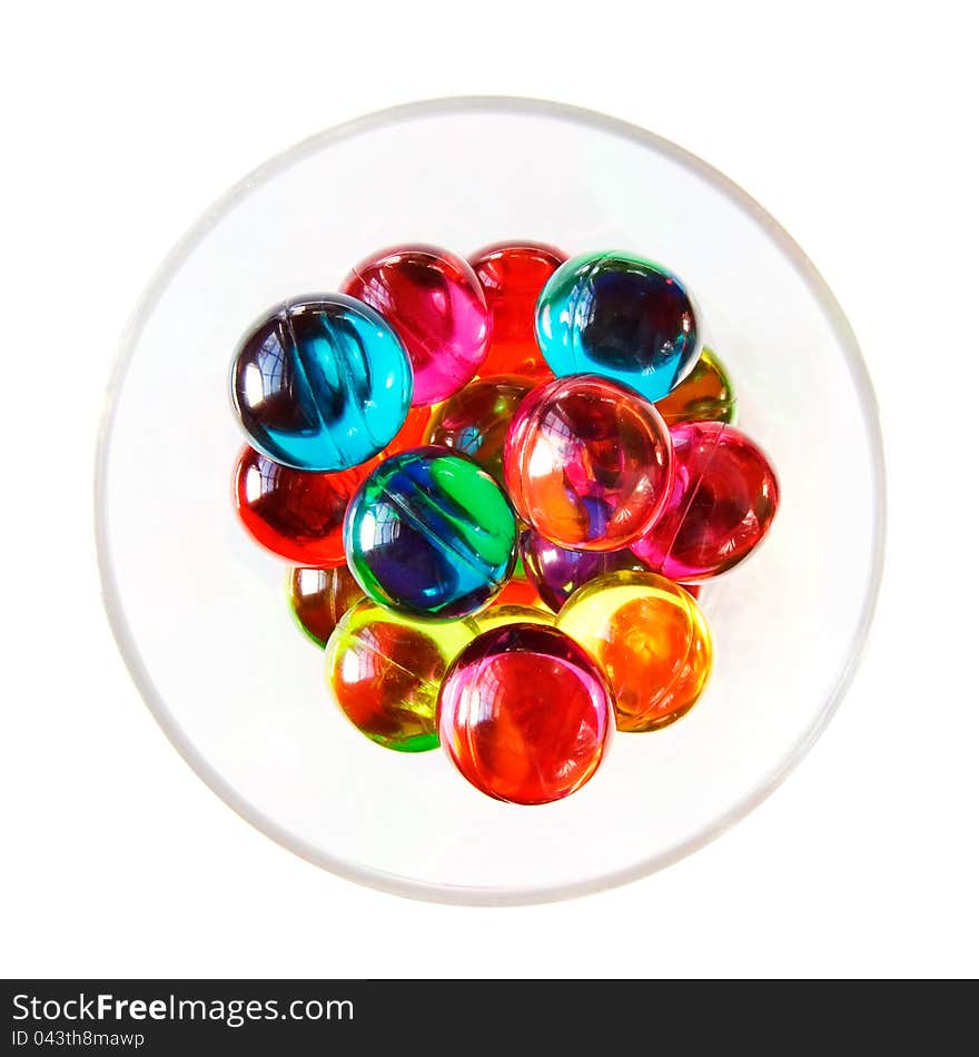 Colourful bath pearls in a glass. Overhead shot. White background. Colourful bath pearls in a glass. Overhead shot. White background.