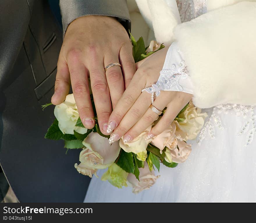 Hand of groom and fiancee on a background a bouquet from roses