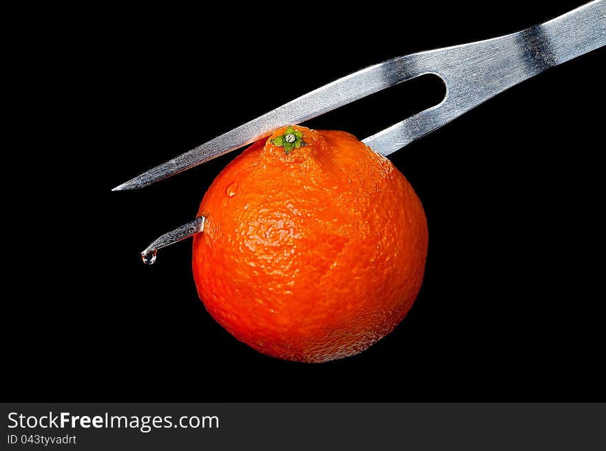 Tangerine on a plug on a black background