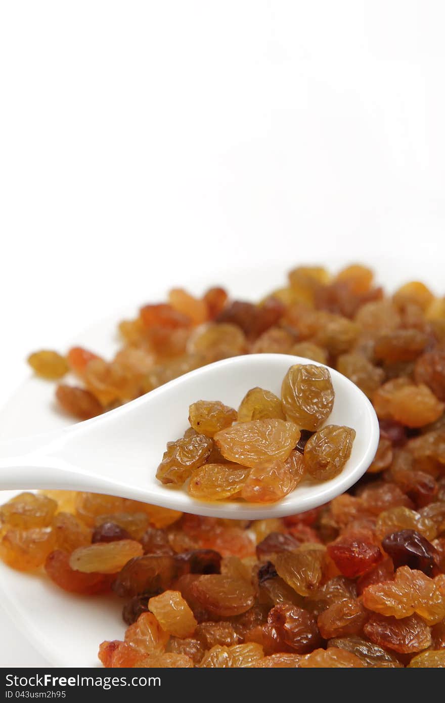 A handful of raisins in a white spoon on white background