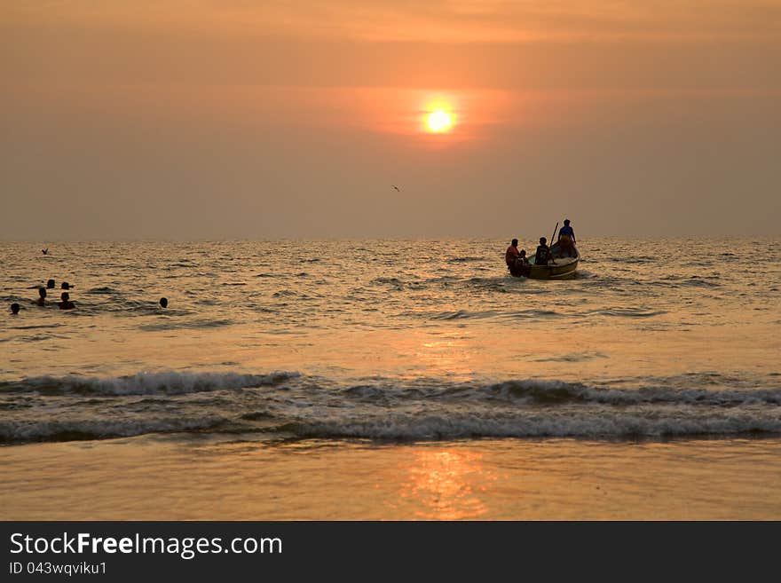 GOA, INDIA - 19 NOV 2011:  indian boat and swimming children at sunset in the seaon Arambol beach in Goa. GOA, INDIA - 19 NOV 2011:  indian boat and swimming children at sunset in the seaon Arambol beach in Goa