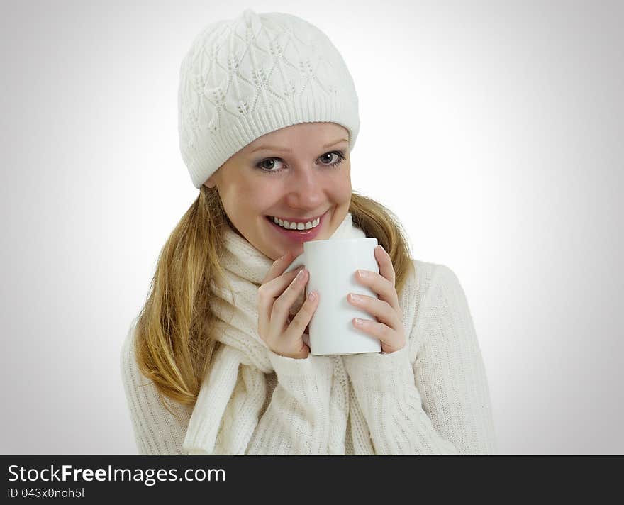 Beautiful happy young woman in a winter hat and scarf with a mug of hot drink. Beautiful happy young woman in a winter hat and scarf with a mug of hot drink
