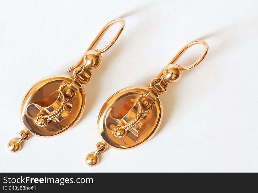 Two bright golden earrings on white background. Two bright golden earrings on white background