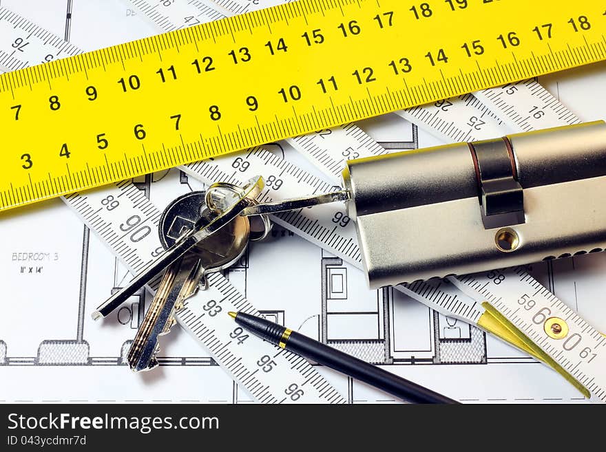 A concept of designing a security in new home; lock, keys, wooden meter and metallic one on blue print of new home. A concept of designing a security in new home; lock, keys, wooden meter and metallic one on blue print of new home.