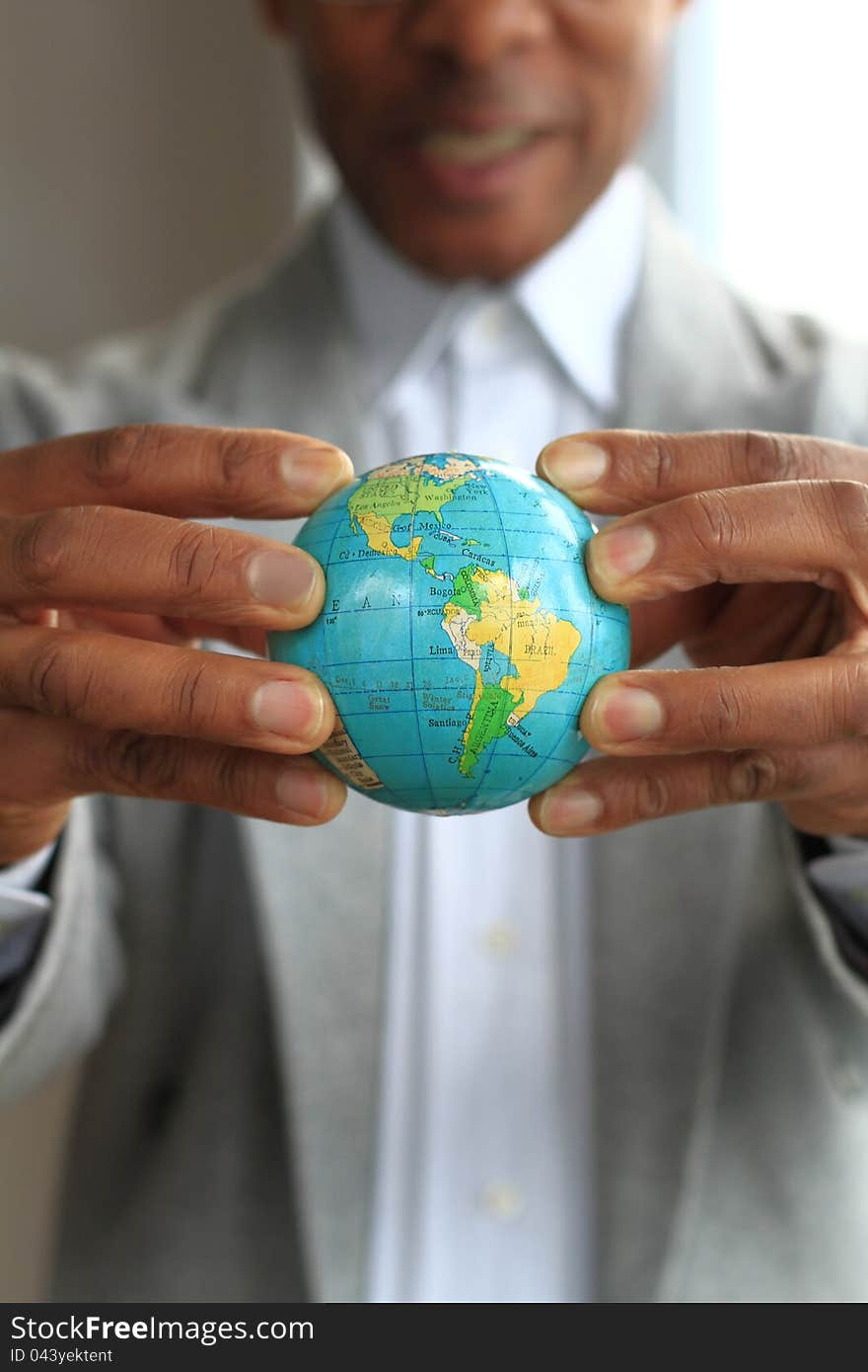 Image of a businessman squashing a globe in his hands