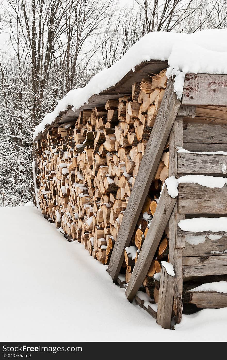 Neatly stacked pile of firewood in winter with fresh snow