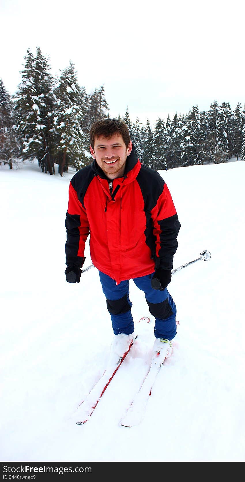 A smiling happy man skiing in a mountain forest