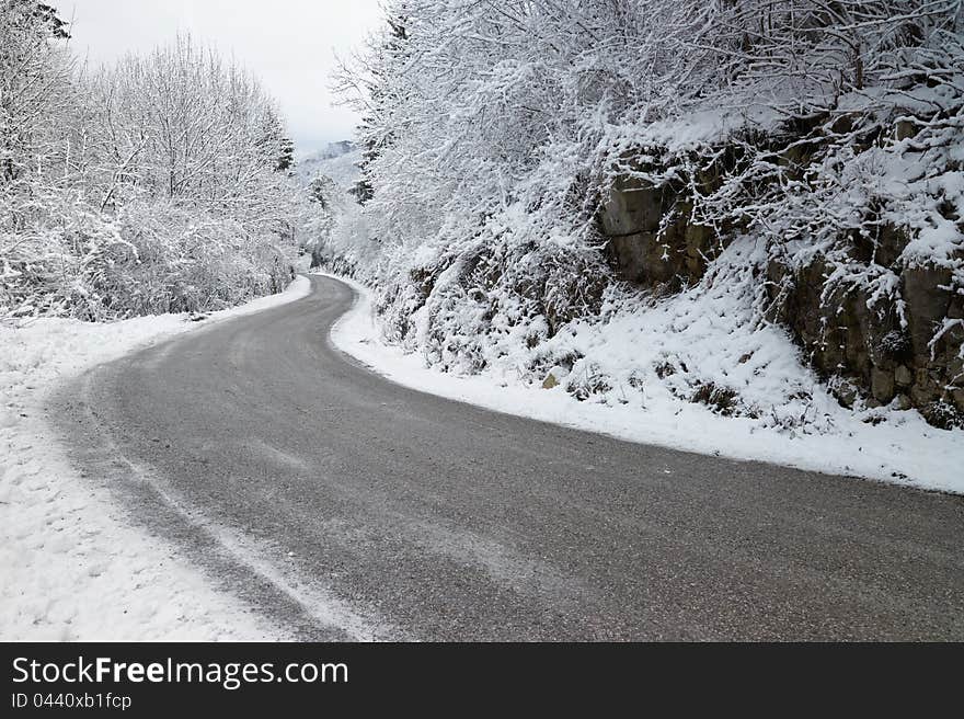 A curve in an empty, icy road through the mountains during winter. A curve in an empty, icy road through the mountains during winter