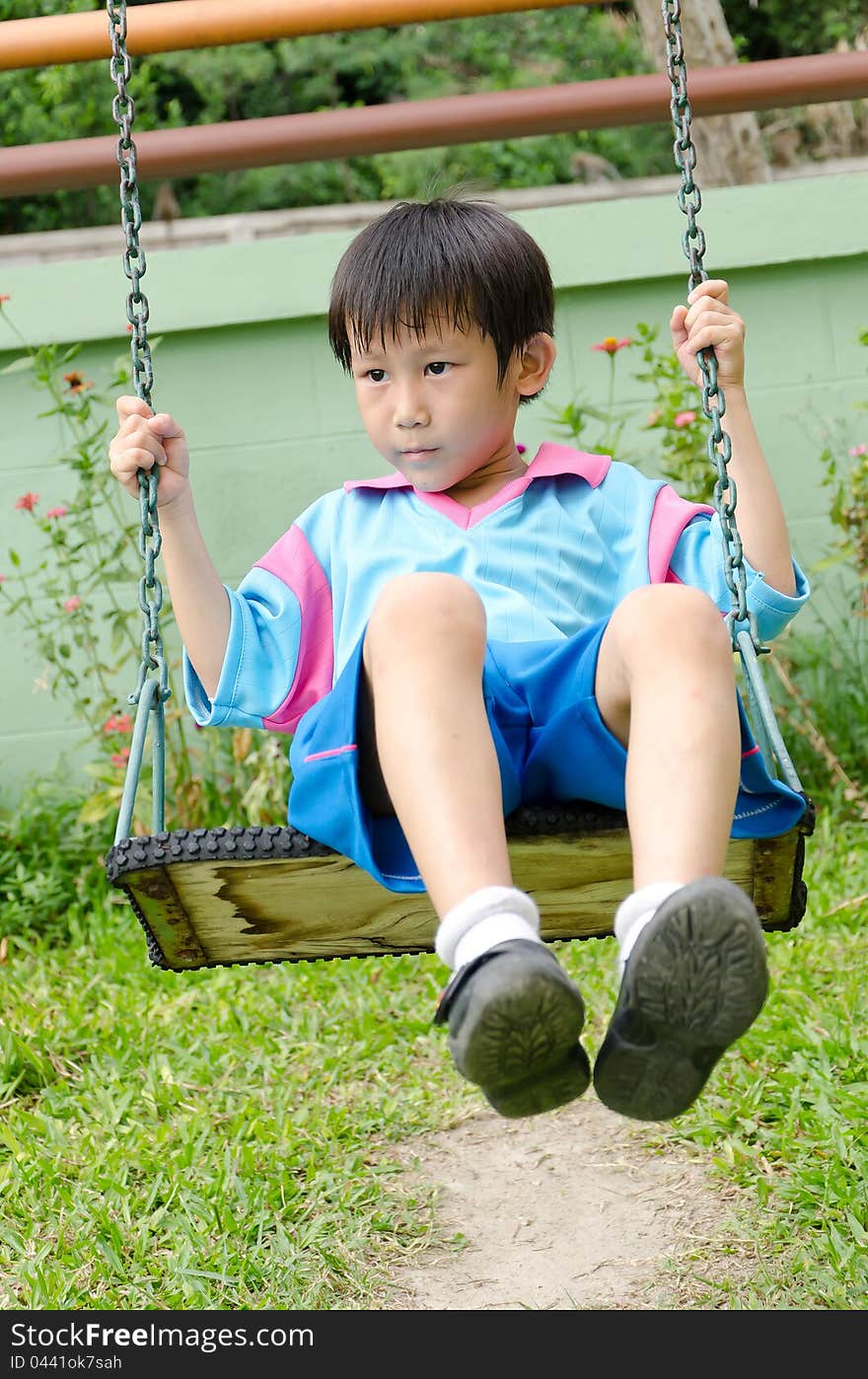 Asian boy playing swing outdoor