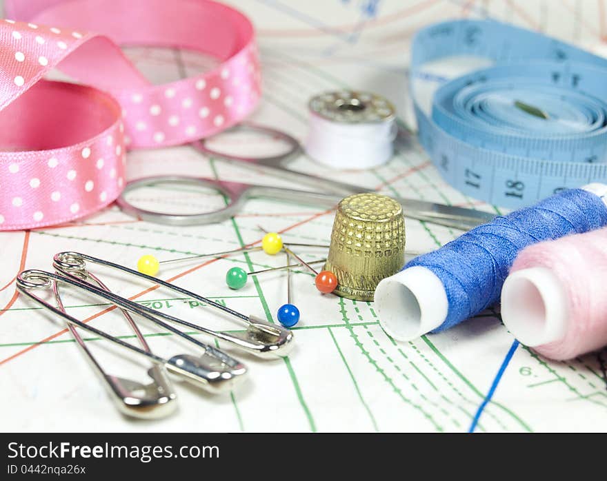 Metal scissors, threads, measuring tape, pins on sewing curve. Metal scissors, threads, measuring tape, pins on sewing curve