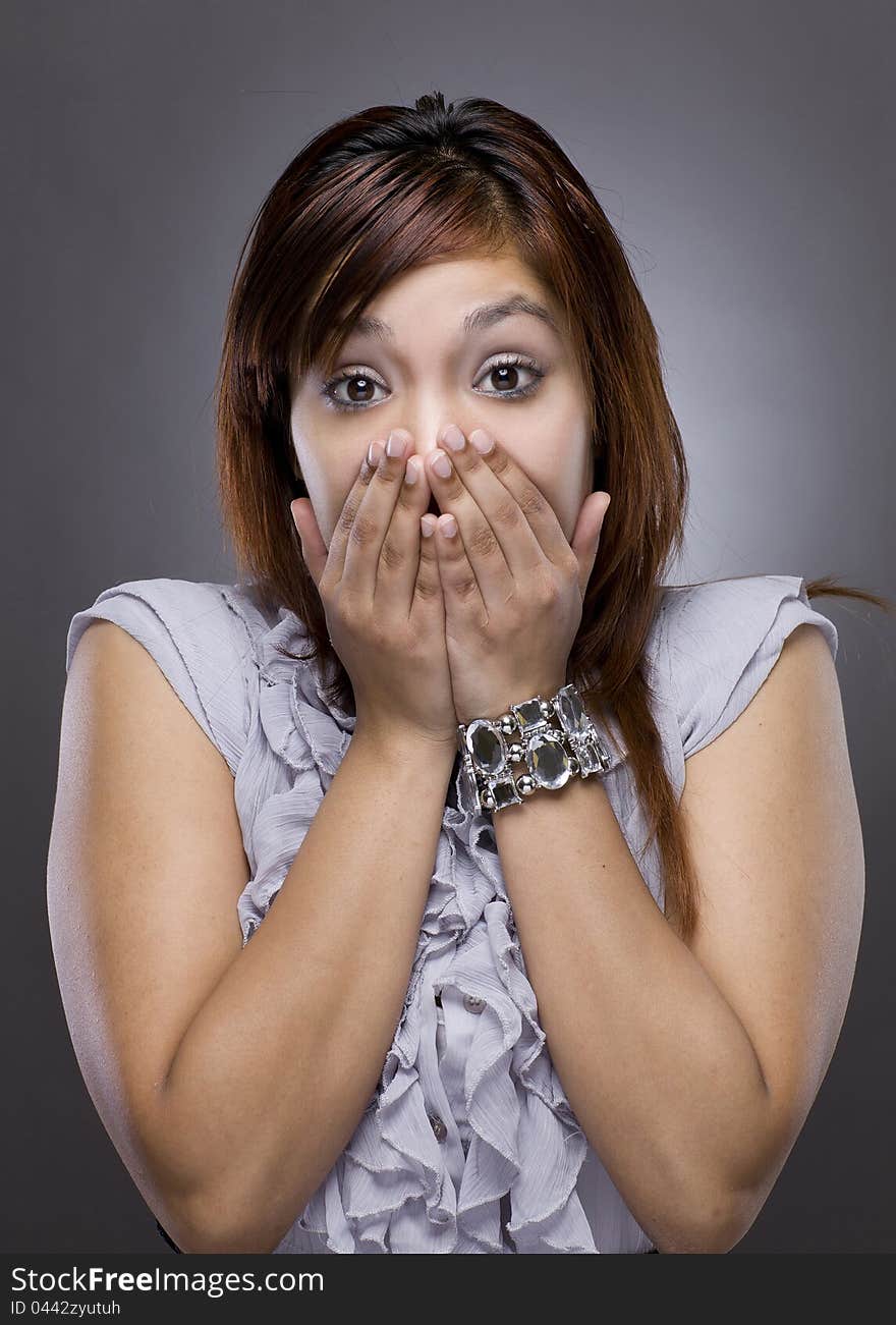 A latino woman puts her hand over her face in shock. A latino woman puts her hand over her face in shock