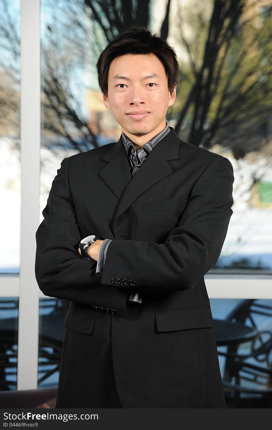 Young Asian Businessman with arms crossed inside an office building