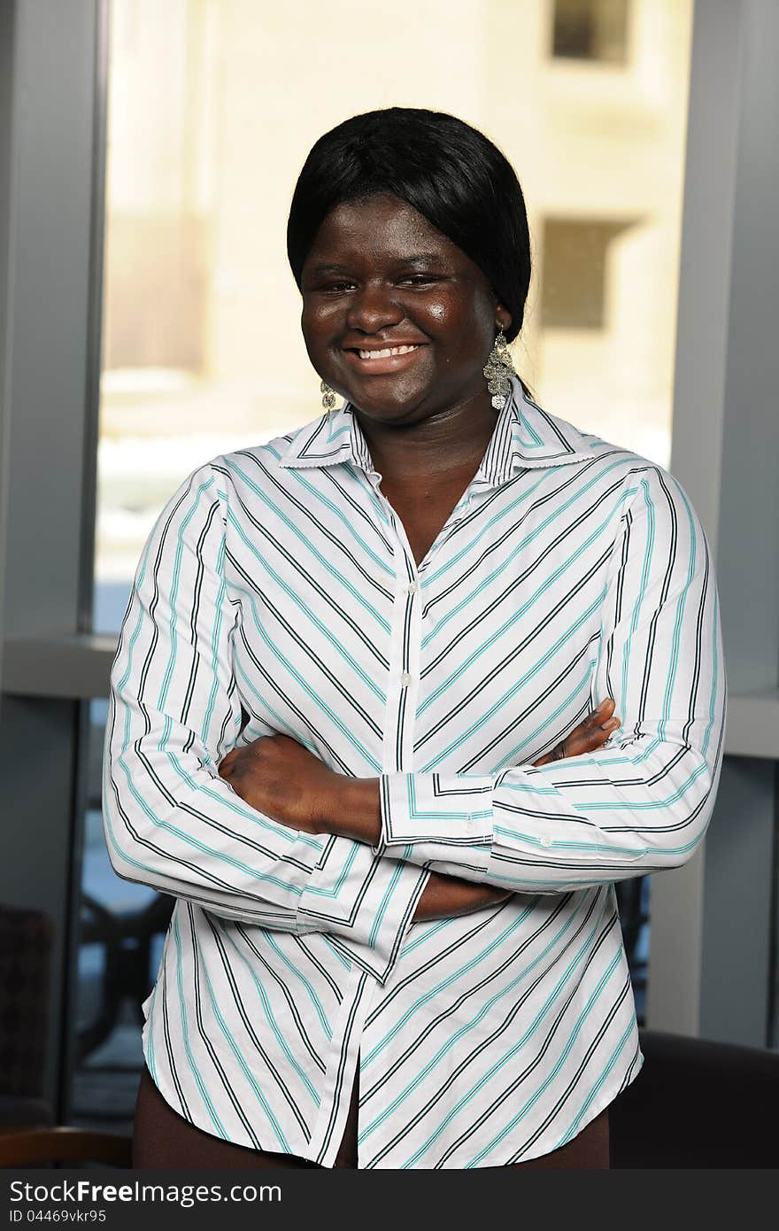 Young African Businessman smiling and with arms crossed inside an office building