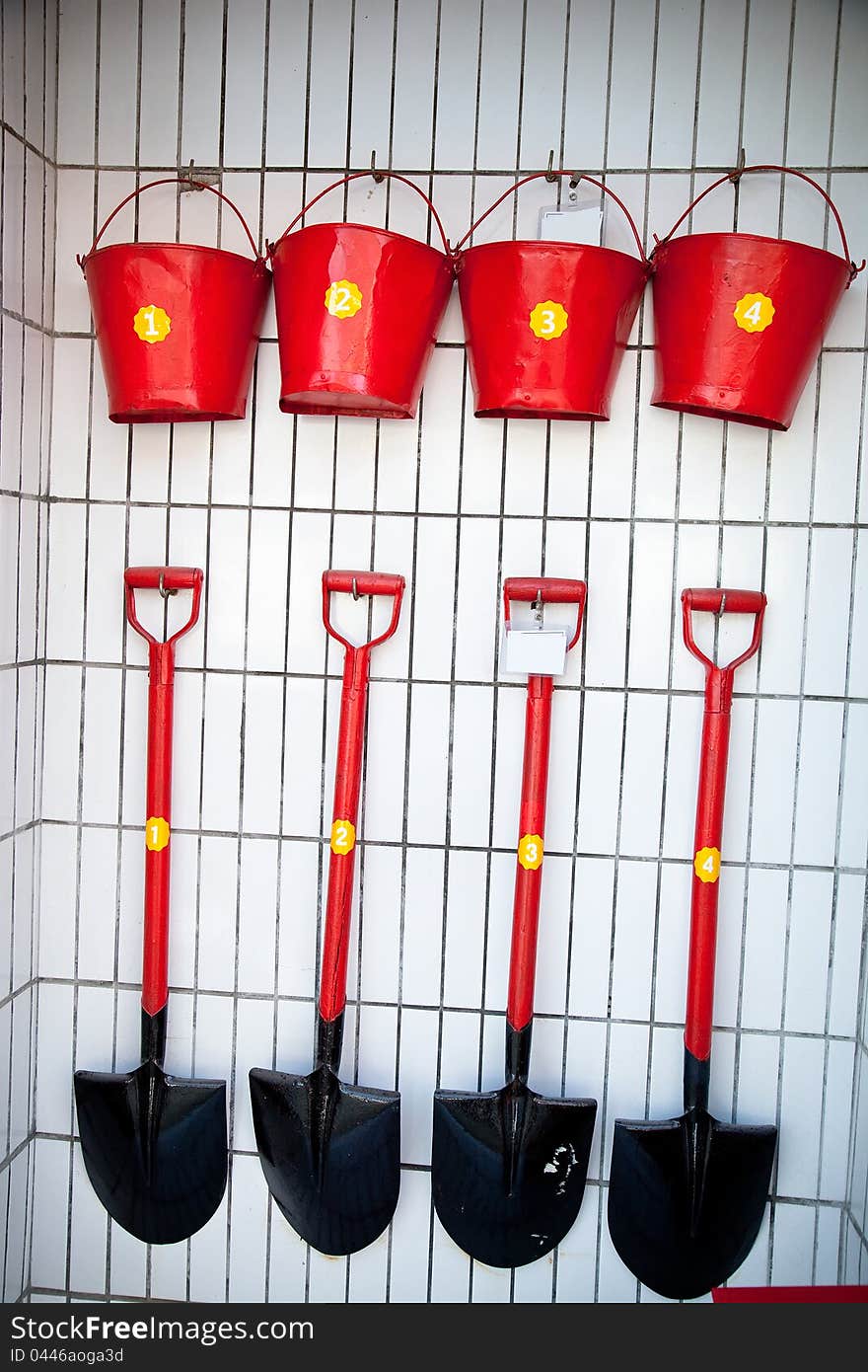 Red shovels and pails neatly hang on the wall. Red shovels and pails neatly hang on the wall