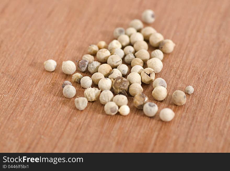 White pepper seeds shot over wooden background