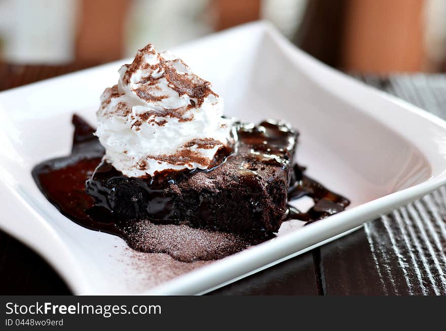 Brownie cake served with chocolate sauce and whipped cream. Brownie cake served with chocolate sauce and whipped cream