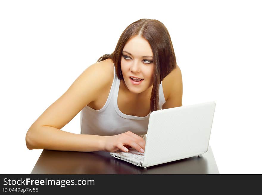 The young woman thinks with the laptop behind a table on a white background. The young woman thinks with the laptop behind a table on a white background