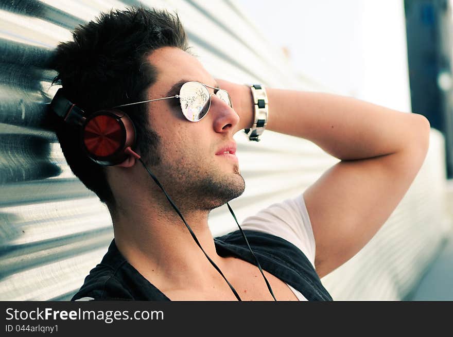 Portrait of handsome man in urban background listening to the music with headphones. Portrait of handsome man in urban background listening to the music with headphones