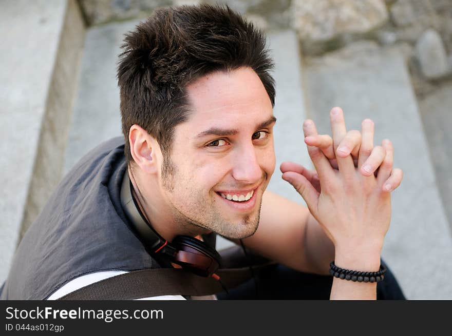 Portrait of young smiling man sitting on steps, with headphones. Portrait of young smiling man sitting on steps, with headphones