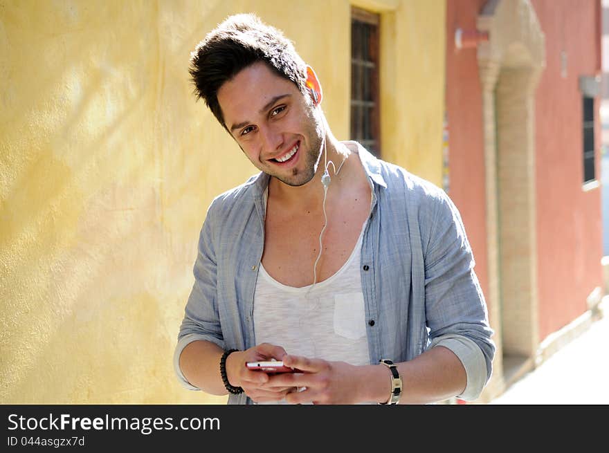 Portrait of handsome man in urban background listening to the music with headphones. Portrait of handsome man in urban background listening to the music with headphones