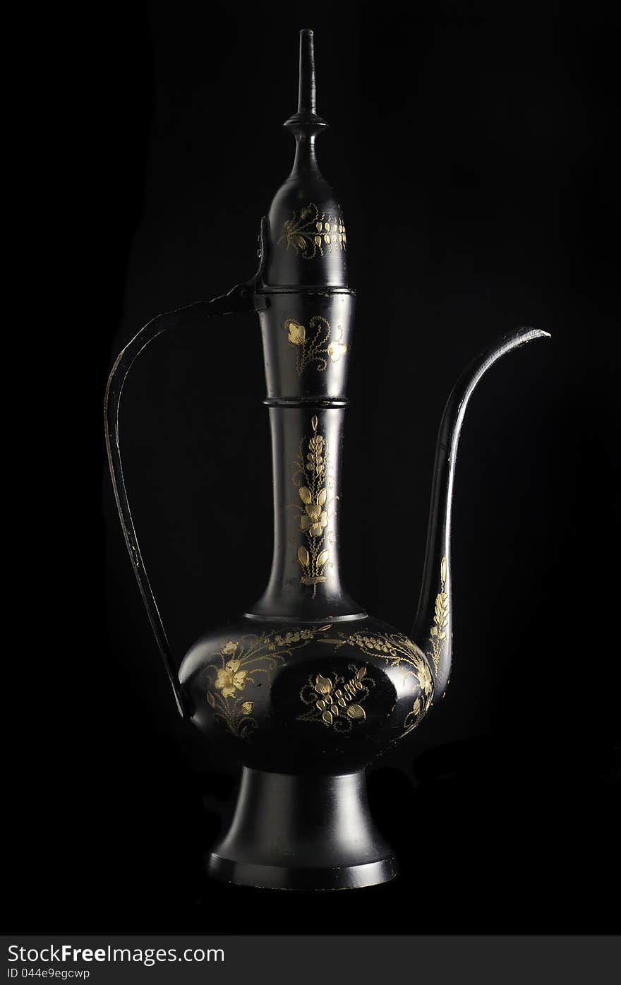 An oriental jug with a decorative floral pattern on a black background. An oriental jug with a decorative floral pattern on a black background