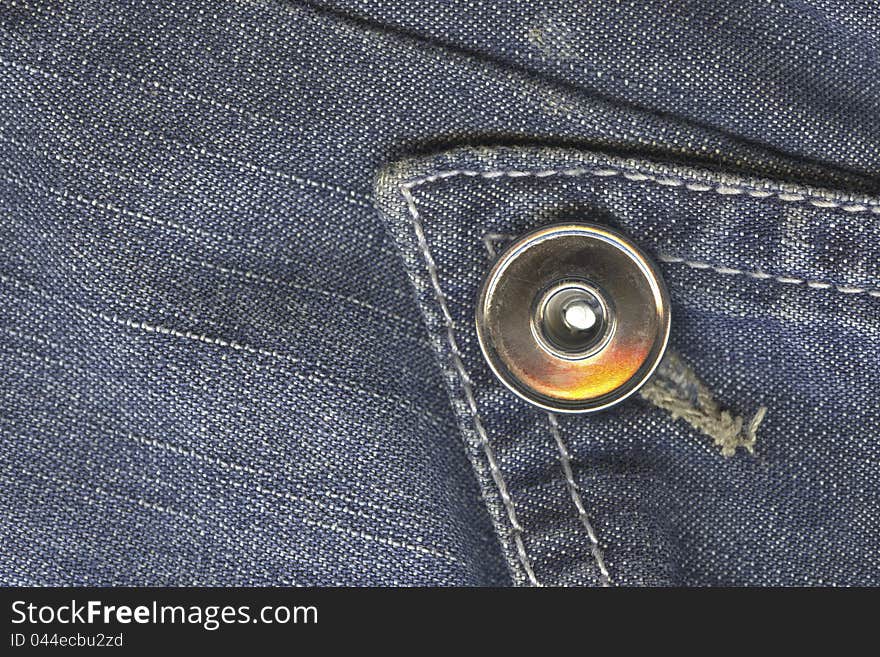 Dark blue jeans textile with fashion metallic button; sharp focus on the button