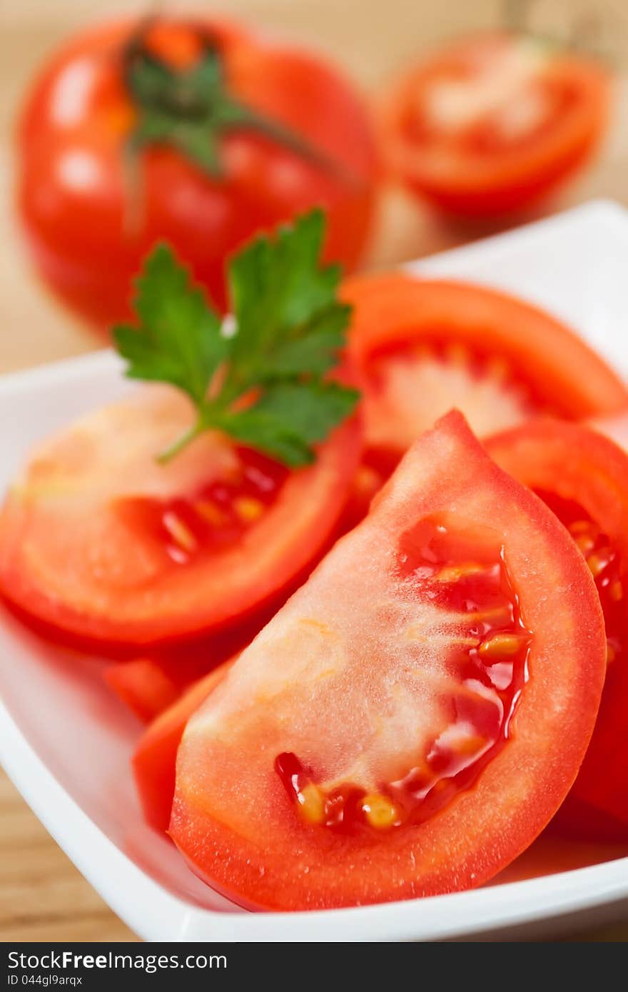 Cut tomatoes in a bowl with a parsley leaf on