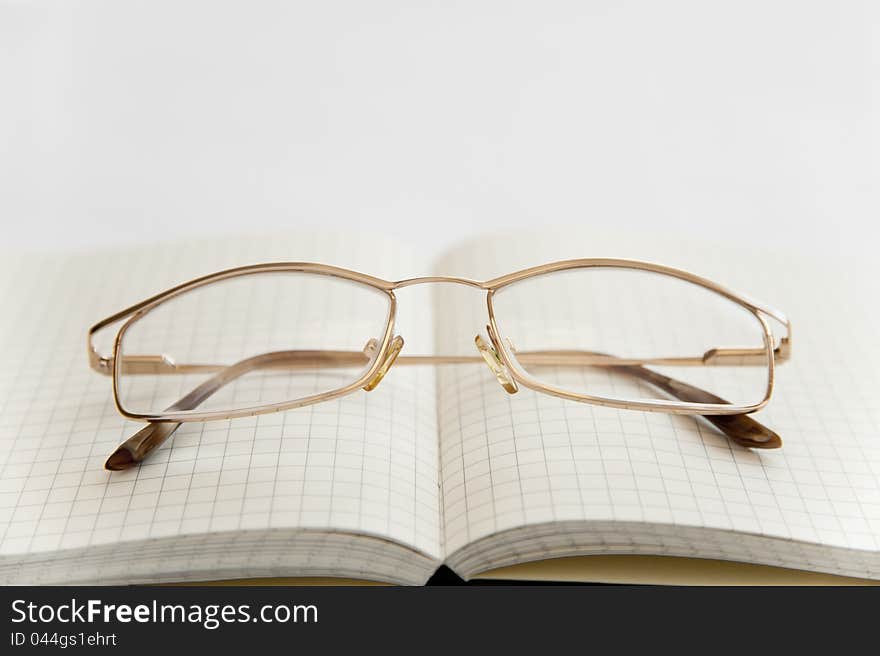 Glasses and notebook on the white background